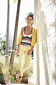 Young brunette woman wearing a striped tankini top, yellow pants and jacket