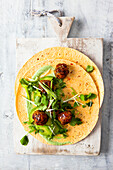 Meatballs with chili sauce, herbs, and avocado on a tortilla wrap