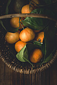 Mandarins with stems and leaves in a wicker basket