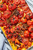 Preparing roasted tomato sauce - Tomatoes with garlic and herbs on a baking tray