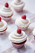 Cupcakes with a cream topping decorated with raspberries