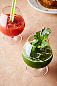 Kale juice and tomato juice in glasses with ice cubes