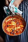 Fish with olives and tomato sauce in a pan