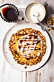 Banana pancake with maple syrup, sour cream and finely chopped walnuts