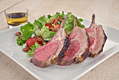 Rack of lamb served with salad with blue cheese, strawberries and bacon