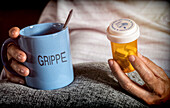 Woman holding a mug and pill bottle