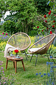 Acapulco garden chair in front of flowerbeds with climbing rose 'Santana' (Rosa) and catmints (Nepeta)