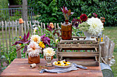 Blumenarrangement mit Dahlien, Rudbeckia und Margeriten auf Gartentisch