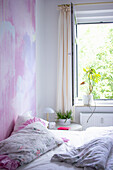 Bed in the bedroom with individual wall design in pink tones