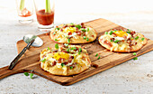 Mini pizza with fried eggs and diced bacon