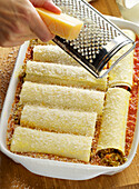Parmesan being grated over cannelloni