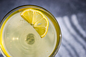 Limocello drink with lemon slice in sun light with shadows