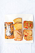 Three loaf cakes: golden raisin bread, lemon bread, and savory bread with tomatoes and peas