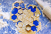 Ausgerollter Teig für Butterplätzchen mit Ausstechform und Kuchenrolle auf blauer Silikonunterlage