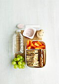 Lunchbox for children with fruit yoghurt, egg, sandwiches, carrots, grapes and mineral water