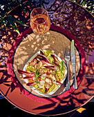Caesar salad with red chicory and radish on an outdoor table