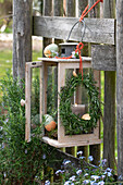Easter decoration in the garden, Easter wreath and eggs hanging from a lantern on a fence, forget-me-not (Myosotis) and rosemary
