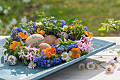 Flower wreath with daisies, hyacinth, dandelion, grape hyacinth, oregano, forget-me-not, violet and garden pansy (Viola wittrockiana), Easter eggs and writing