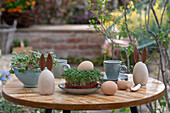 Osterdekoration, Eier, gebastelte Hasenfiguren, Sprossen auf Terrassentisch