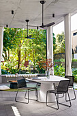 Round, white table with black chairs on terrace with high ceiling