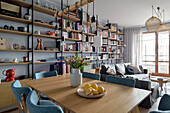 Living room with dining area, seating area, and floor-to-ceiling shelving unit