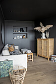 Light sofa with cushions and highboard in the living room with black walls