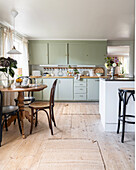 Wohnküche mit Holztisch, Küchentheke und Küchenzeile in Mintgrün