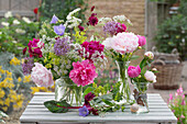 Sommerliches Blütenarrangement in Vasen mit Pfingstrosen, Zierlauch, Glockenblumen, Giersch und Frauenmantel