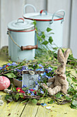 Old baking tin with wreath of forget-me-nots and birch twigs, fabric Easter bunny and enamel pots