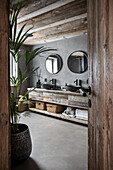 Blick ins Badezimmer mit grauen Wänden auf Waschtisch aus Recyclingholz
