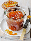 Homemade marmalade in jar with brown bread toast and knife
