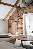 Wooden wall with wooden door in the attic room, ladder leads to the small alcove