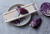 Red cabbage being sliced with a vegetable slicer