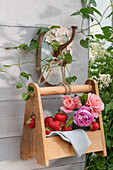 Frische Erdbeeren und Rosen in Flaschenträger als sommerliche Dekoration