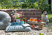 Bouquet and jug with strawberries on cushion in garden next to bench with drinks