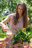 Garden party in summer: Young woman pouring rosé champagne into glass