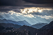 Sun rays filter between black clouds at sunset, Stelvio Mountain pass, Stelvio National Park, Valtellina, Lombardy, Italy, Europe