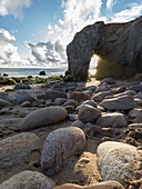 Steine am Strand, das Licht fällt durch den natürlichen Bogen von Port Blanc, Quiberon, Bretagne, Frankreich, Europa