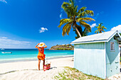 Schöne Frau mit Strohhut und Kleid entspannt sich am tropischen Strand, Antigua, Leeward Islands, Westindische Inseln, Karibik, Mittelamerika