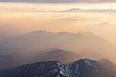 Luftaufnahme des Nebels bei Sonnenuntergang über den majestätischen Lepontinischen Alpen und dem Monte Rosa in den Wolken, Blick aus dem Flugzeug, Schweiz, Europa