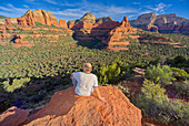 A man sitting on the top of Mescal Mountain overlooking Deadmans Pass in Sedona, Arizona, United States of America, North America