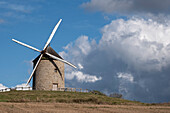 Windmühle auf einem Hügel mit blauem Himmel und weißen Wolken, Normandie, Frankreich, Europa