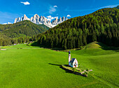 Luftaufnahme der Geislergruppe und der ikonischen Johanneskapelle in Ranui im Frühling, St. Magdalena, Funes Tal, Dolomiten, Südtirol, Italien, Europa