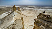 Frau sitzt auf einem riesigen Felsen, Bozzhira-Schlucht, Ustyurt-Hochebene, Mangystau, Kasachstan, Zentralasien, Asien