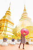 Woman with red umbrella at Wat Phra Singh Woramahawihan, Chiang Mai, Thailand, Southeast Asia, Asia