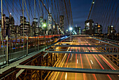 Verkehr über die Brooklyn Bridge mit der Skyline von Manhattan dahinter bei Nacht, Manhattan, New York, Vereinigte Staaten von Amerika, Nordamerika