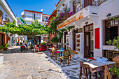 Blick auf die Tavernen in der weiß getünchten Straße in Skiathos-Stadt, Insel Skiathos, Sporaden, Griechische Inseln, Griechenland, Europa