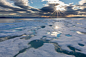 Sunburst over fast ice in Lancaster Sound, between Devon Island and Baffin Island, Nunavut, Canada, North America