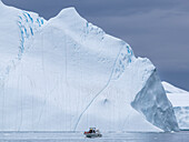 Touristen, die eine Eistour in einem kleinen Boot unternehmen und Eisberge aus dem Ilulissat-Eisfjord beobachten, kurz vor Ilulissat, Grönland, Dänemark, Polarregionen