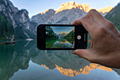 Phone screen with a picture of Lake Braies at sunrise, Dolomites, Alto Adige, Italy, Europe